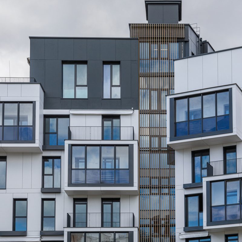 Outside view on upper floors of modern white and grey building with balconies Multilogement